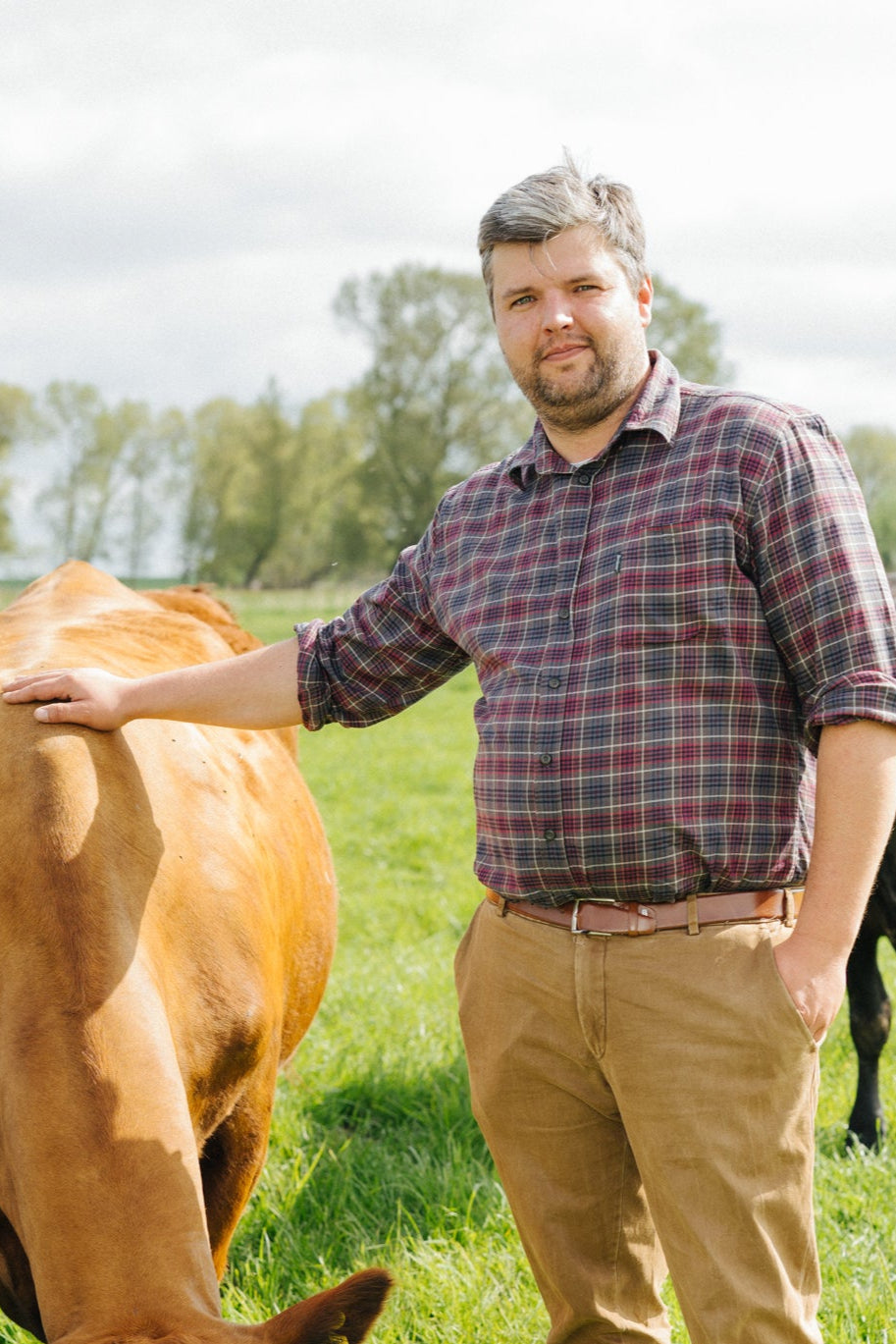 Andreas Winter streichelt ein Rind auf der Krautsand Farm